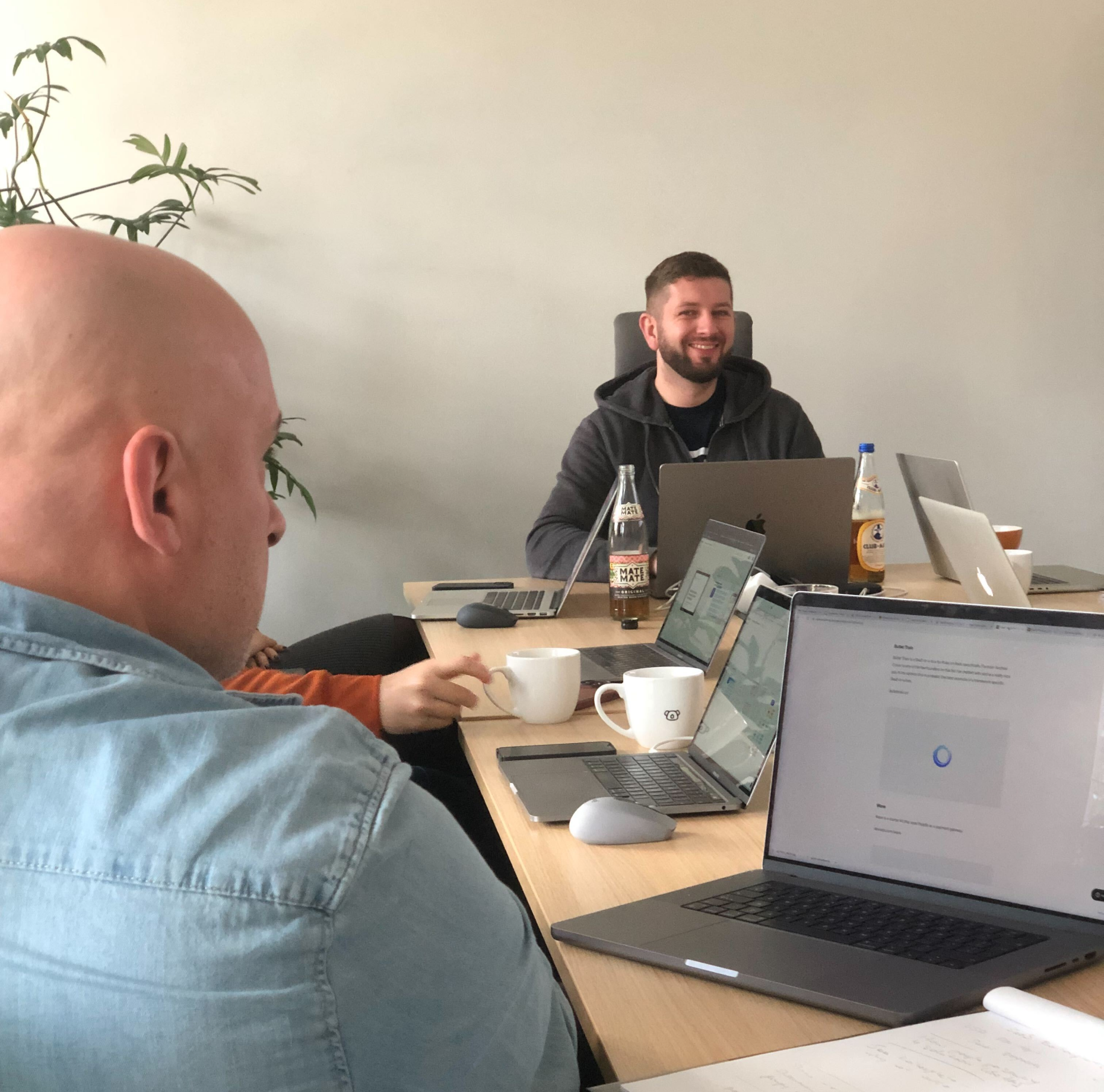 Two people sitting at table with laptops and coffee cups
