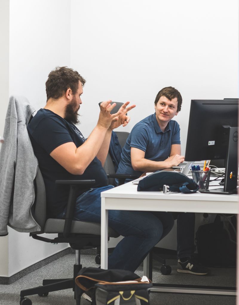 Two people having a discussion sitting at a desk in Apptension office