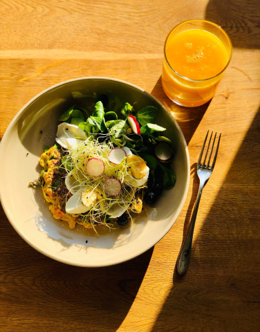 A colorful plate of food with a glass of juice beside it